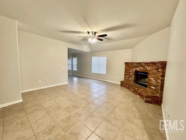 unfurnished living room featuring light tile patterned floors, a fireplace, baseboards, and ceiling fan