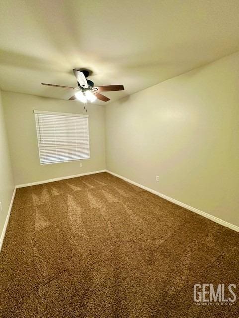 unfurnished room featuring a ceiling fan, baseboards, and dark colored carpet