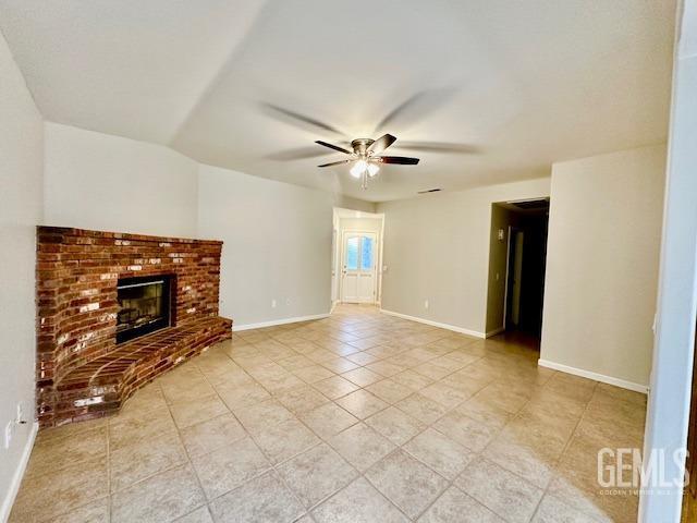 unfurnished living room with baseboards, a brick fireplace, light tile patterned flooring, and a ceiling fan