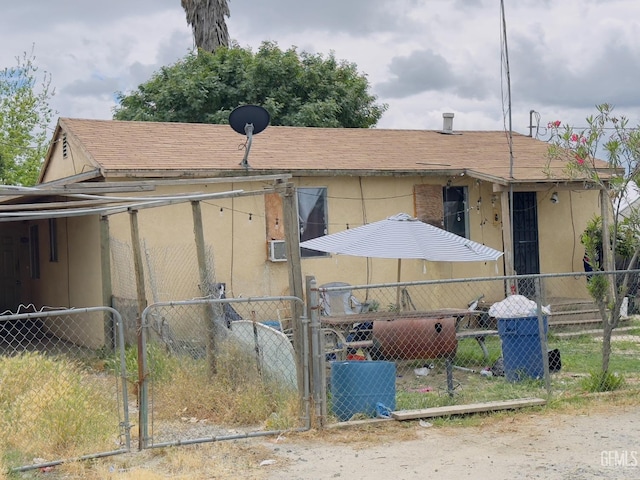 exterior space featuring fence, a gate, a shingled roof, and stucco siding