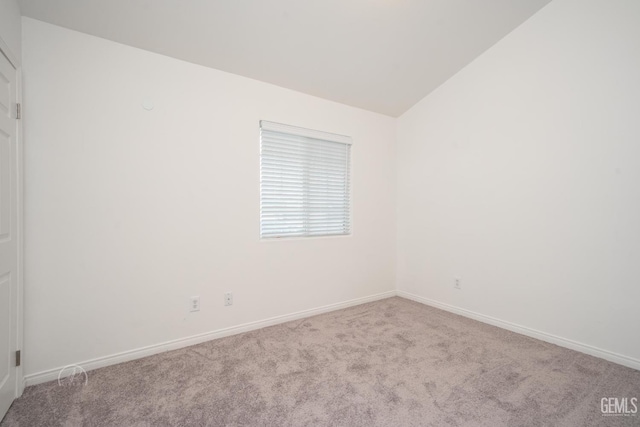 spare room featuring vaulted ceiling and light carpet