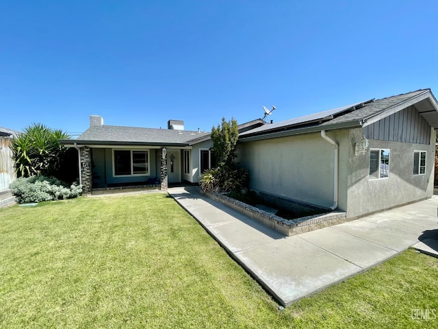 320 E Woodrow St, Taft, CA 93268 - rear view of property featuring roof mounted solar panels, a yard, stucco siding, and a chimney
