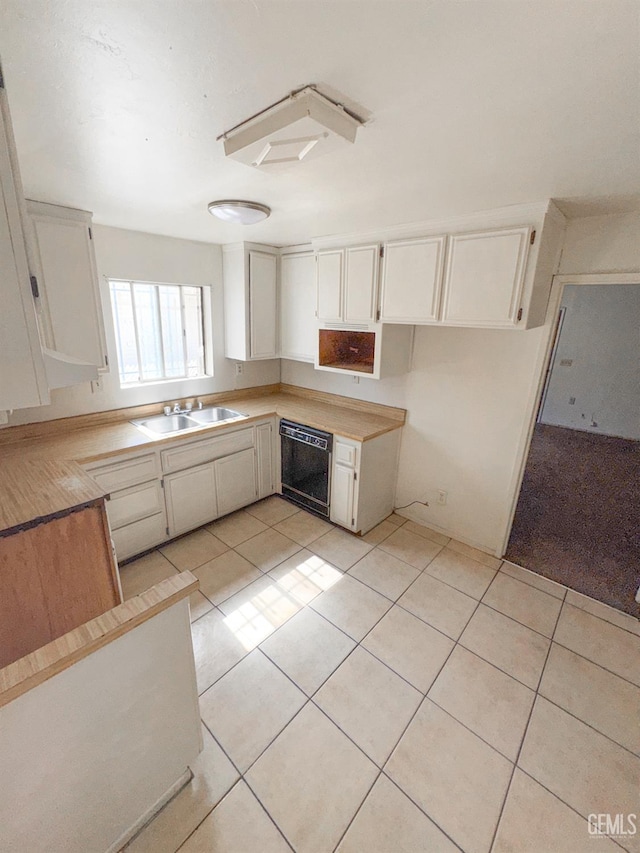 1065 12th St, Wasco, CA 93280 - kitchen featuring black dishwasher, light tile patterned floors, light countertops, and white cabinetry