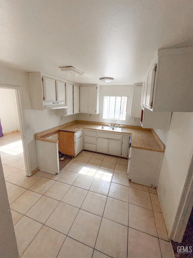 1065 12th St, Wasco, CA 93280 - kitchen with under cabinet range hood, light tile patterned flooring, and light countertops