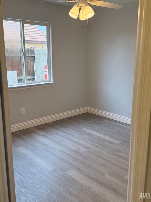 unfurnished room with ceiling fan, baseboards, and wood finished floors