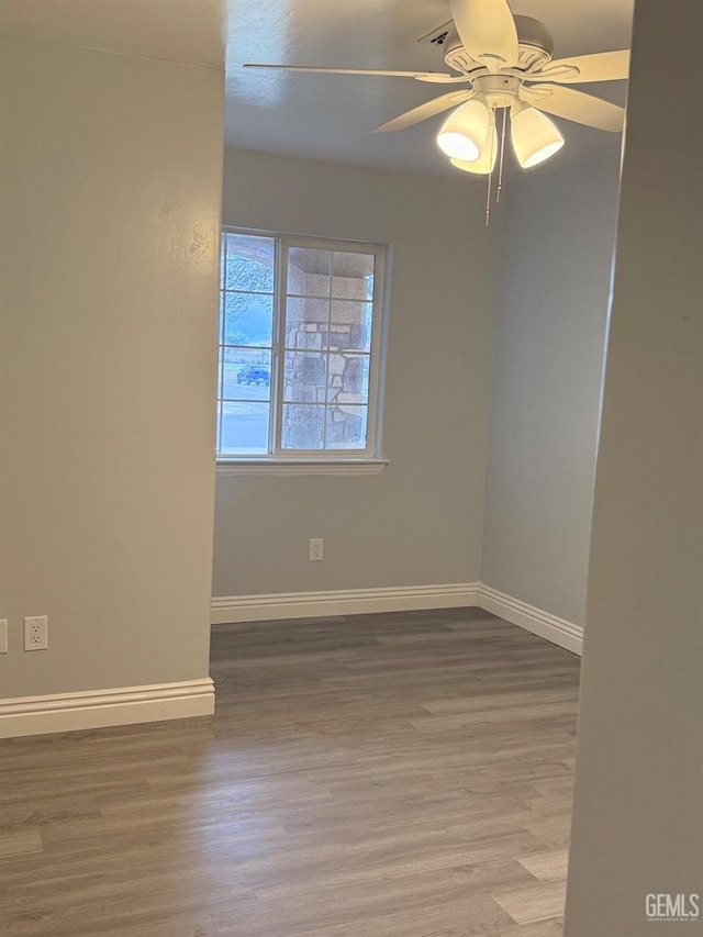 empty room with ceiling fan, baseboards, and wood finished floors