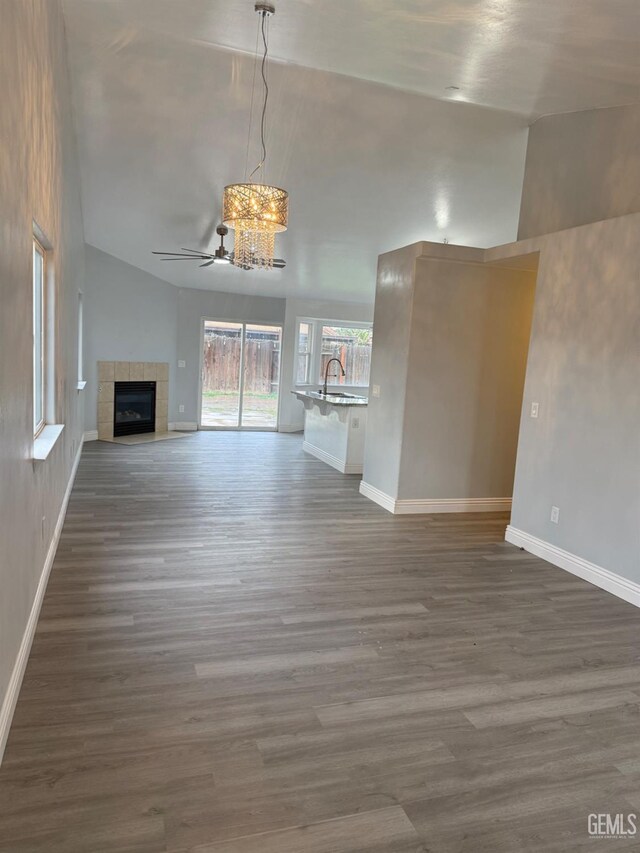 unfurnished living room featuring vaulted ceiling, dark wood-type flooring, a fireplace, and baseboards