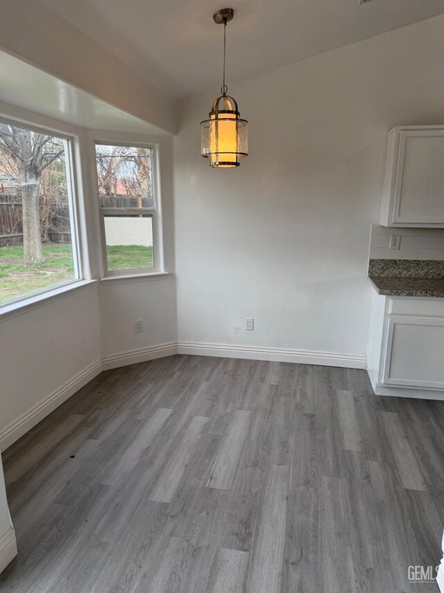 unfurnished dining area featuring light wood-style flooring and baseboards