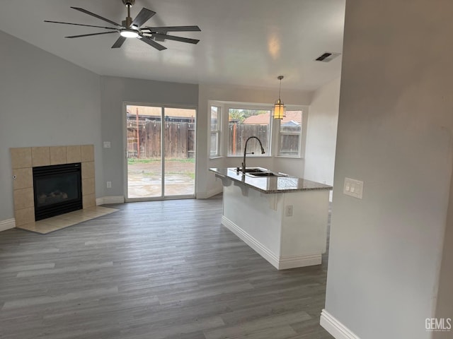 kitchen featuring a sink, visible vents, open floor plan, hanging light fixtures, and a kitchen bar