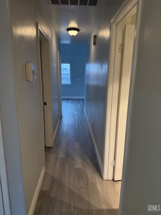 hallway featuring baseboards, visible vents, and dark wood-type flooring