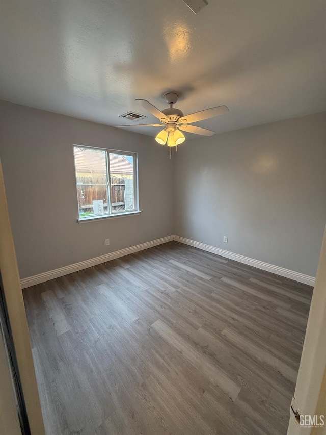 unfurnished room featuring a ceiling fan, visible vents, baseboards, and wood finished floors