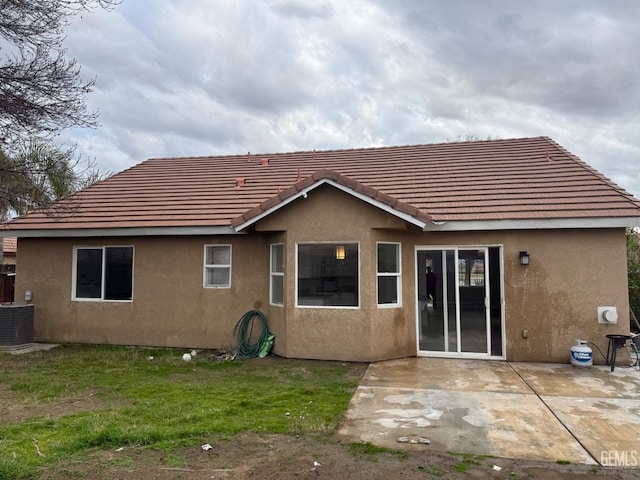 rear view of property with a tile roof, a patio area, central AC, and stucco siding