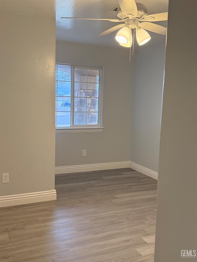 spare room with baseboards, ceiling fan, and light wood-style floors