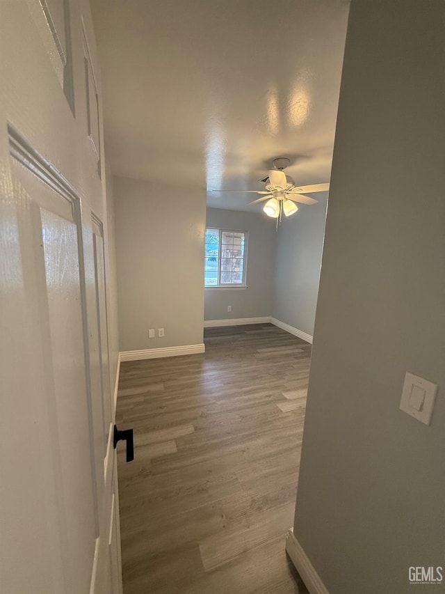 spare room featuring wood finished floors, a ceiling fan, and baseboards