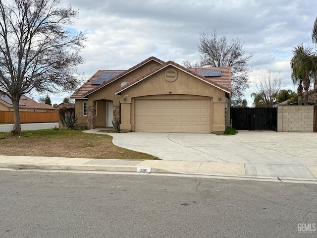 view of front of property with an attached garage, solar panels, a tiled roof, driveway, and stucco siding