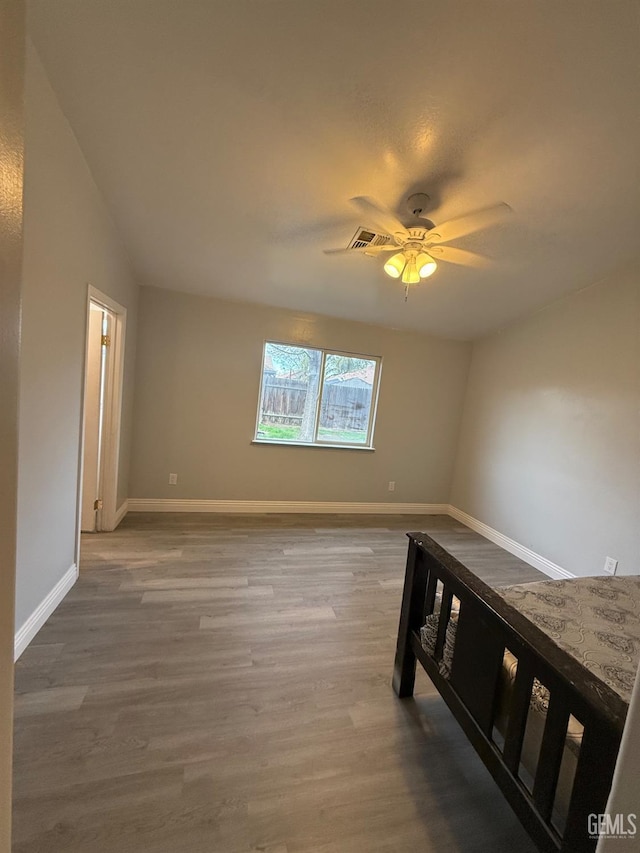 spare room featuring a ceiling fan, visible vents, baseboards, and wood finished floors