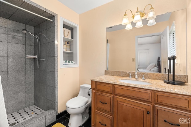 bathroom with tile patterned flooring, vanity, a tile shower, and toilet