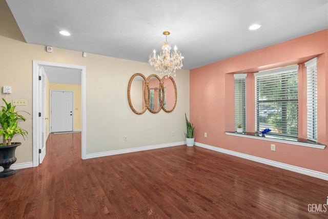 empty room featuring a chandelier and hardwood / wood-style floors