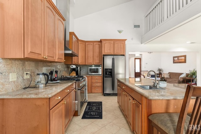 kitchen with appliances with stainless steel finishes, sink, decorative backsplash, a kitchen island with sink, and light stone counters