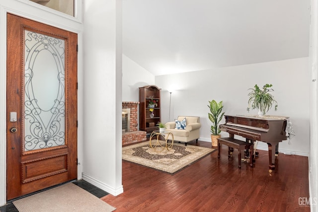 foyer entrance with lofted ceiling, a fireplace, and wood-type flooring