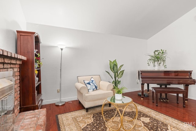 sitting room with dark wood-type flooring, lofted ceiling, and a fireplace