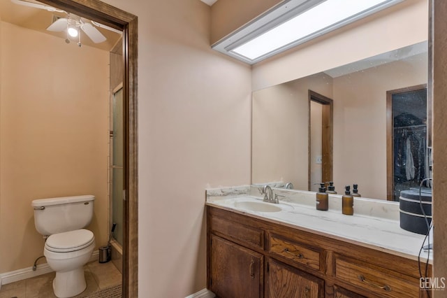 bathroom with tile patterned floors, toilet, vanity, a shower with door, and ceiling fan