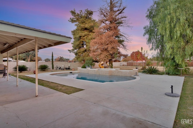 pool at dusk featuring a patio area