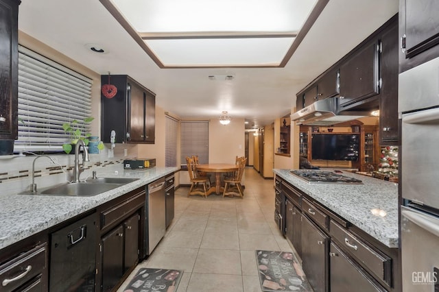 kitchen featuring sink, light tile patterned floors, dark brown cabinetry, stainless steel appliances, and light stone countertops