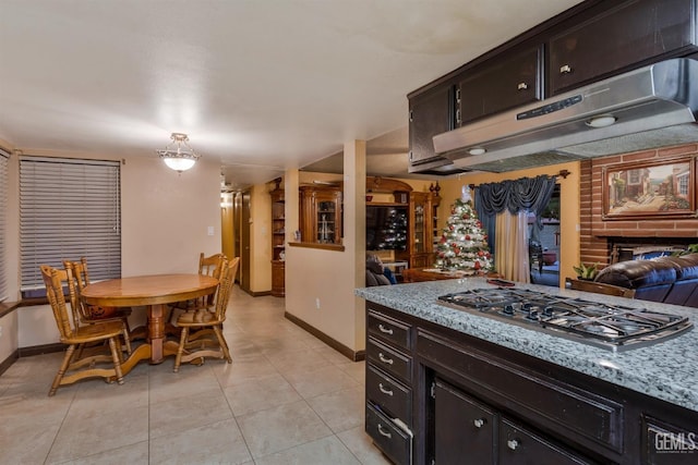 kitchen with pendant lighting, light stone countertops, stainless steel gas stovetop, and light tile patterned flooring