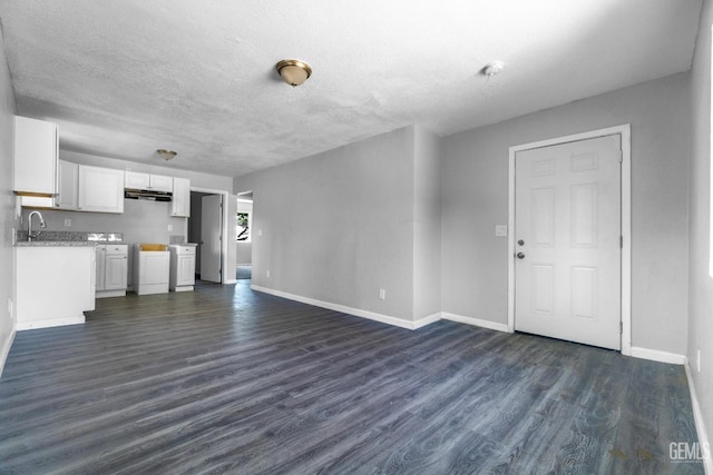 unfurnished living room with a textured ceiling, dark hardwood / wood-style floors, and washing machine and dryer