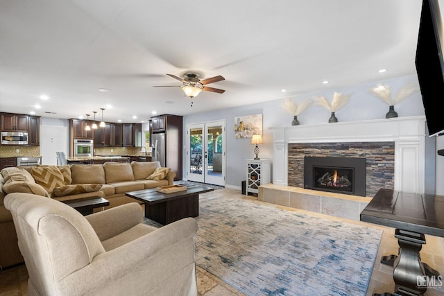 living room featuring ceiling fan, a fireplace, and french doors