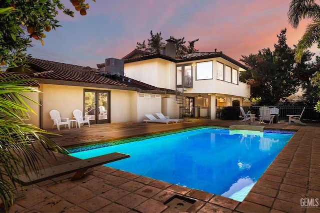 pool at dusk with a patio area and central air condition unit