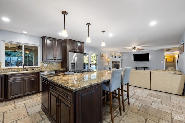 kitchen featuring sink, hanging light fixtures, backsplash, a kitchen bar, and appliances with stainless steel finishes