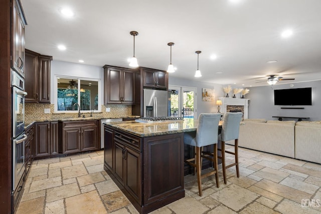 kitchen featuring pendant lighting, a kitchen island, backsplash, and stainless steel appliances