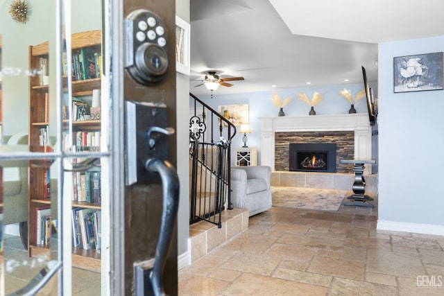 interior space with ceiling fan and a stone fireplace