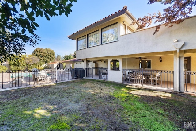 back of house with ceiling fan, a yard, and a patio