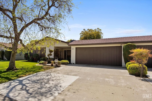 view of front of home featuring a front lawn, driveway, stucco siding, and a garage