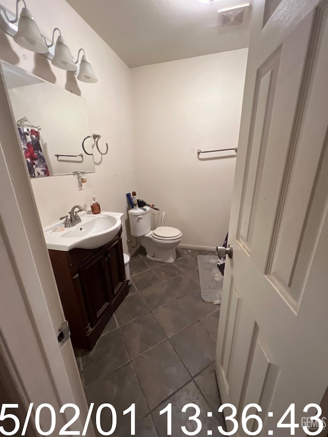 bathroom with toilet, visible vents, vanity, and tile patterned floors