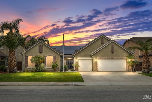 view of front of home featuring a lawn, solar panels, and a garage