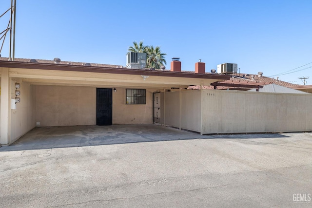 2848 Summit Cir, Bakersfield, CA 93306 - view of front of house with cooling unit, a chimney, stucco siding, and a carport
