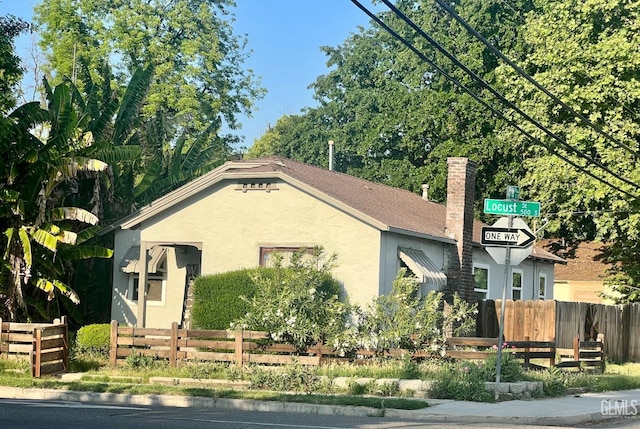 ranch-style house featuring fence, stucco siding, and a chimney