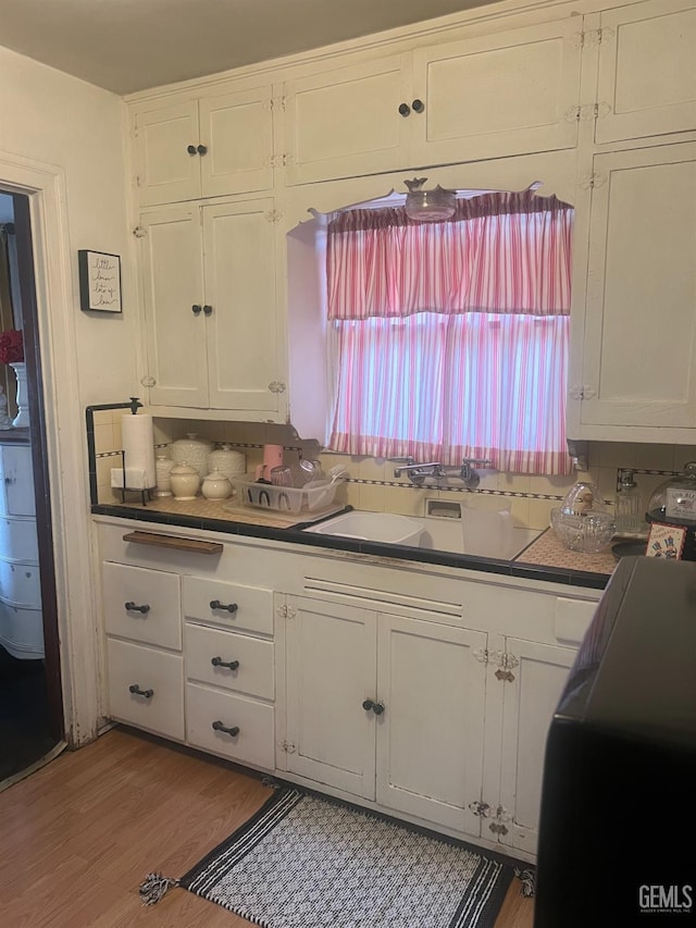kitchen with white cabinetry, decorative backsplash, and a sink