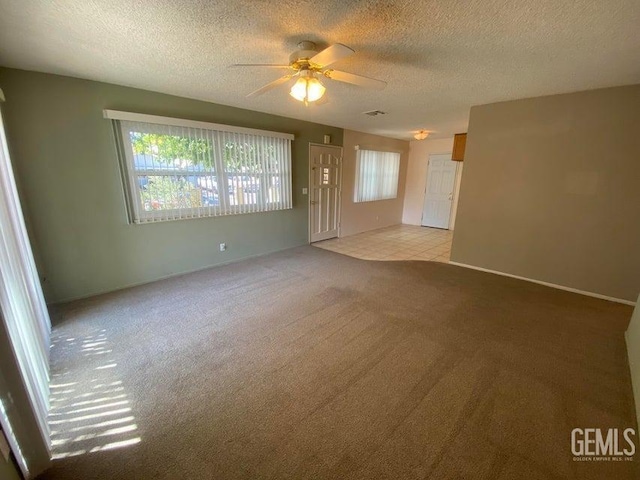 unfurnished living room featuring ceiling fan, light colored carpet, and a textured ceiling