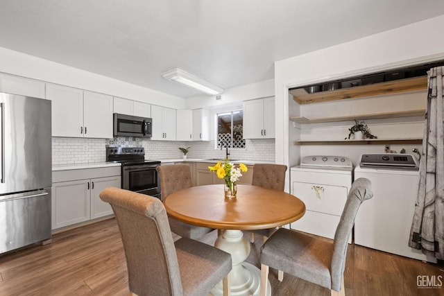 kitchen featuring washing machine and clothes dryer, white cabinetry, tasteful backsplash, stainless steel appliances, and light hardwood / wood-style floors