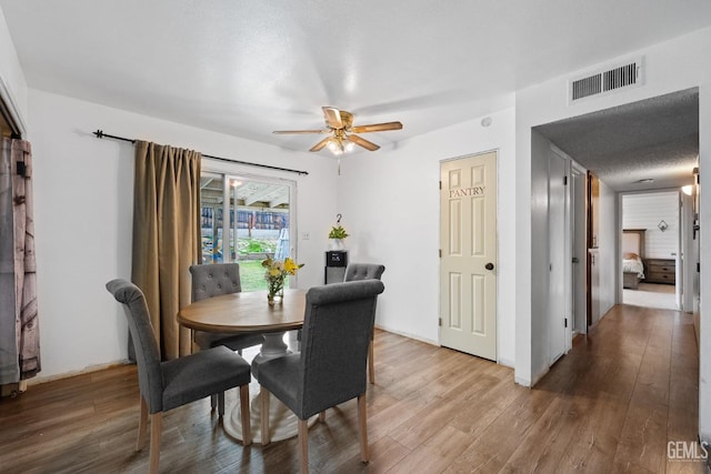 dining room with hardwood / wood-style flooring, ceiling fan, and a textured ceiling