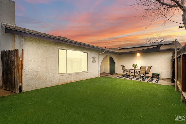 back house at dusk with a yard and a patio