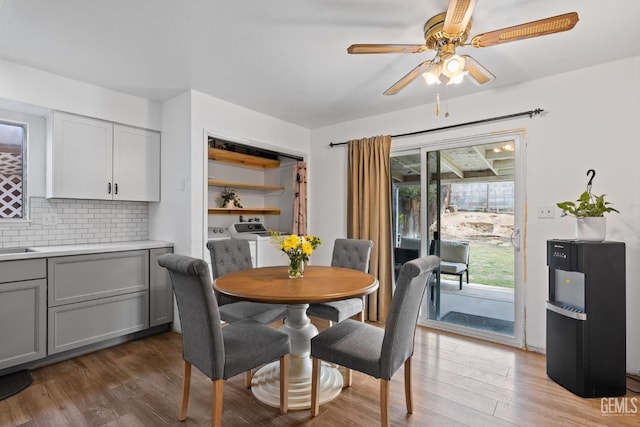 dining area featuring washing machine and dryer, wood-type flooring, sink, and ceiling fan