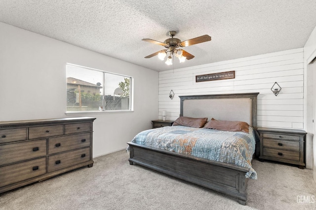 carpeted bedroom featuring ceiling fan, a textured ceiling, and wood walls