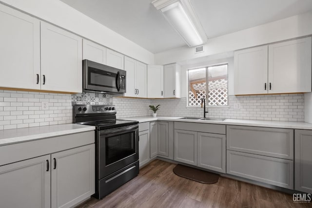 kitchen featuring sink, tasteful backsplash, range with electric stovetop, dark hardwood / wood-style flooring, and gray cabinets