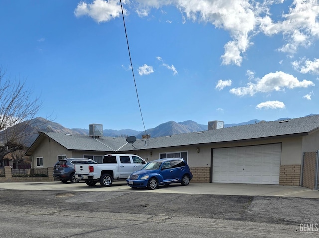 ranch-style home featuring a mountain view, a garage, and central AC unit